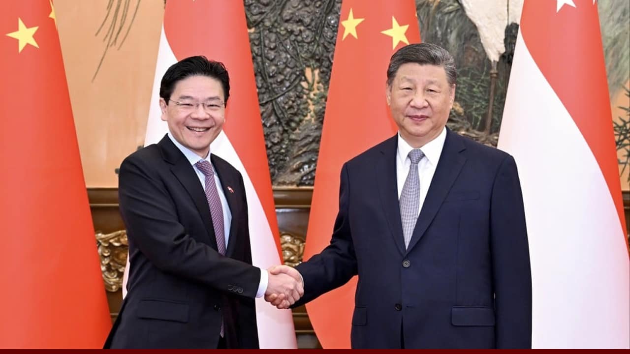 Two Asian leaders shake hands in front of national flags